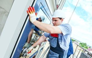 Two builders worker installing glass windows on facade of business building using glass suction plates